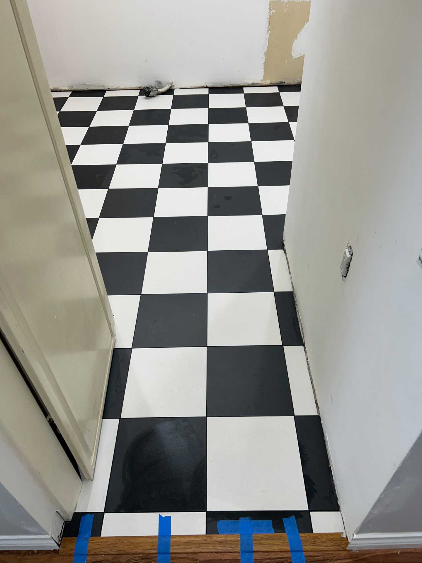 Checkerboard tile floor doorway transition to hardwood with clean grout lines