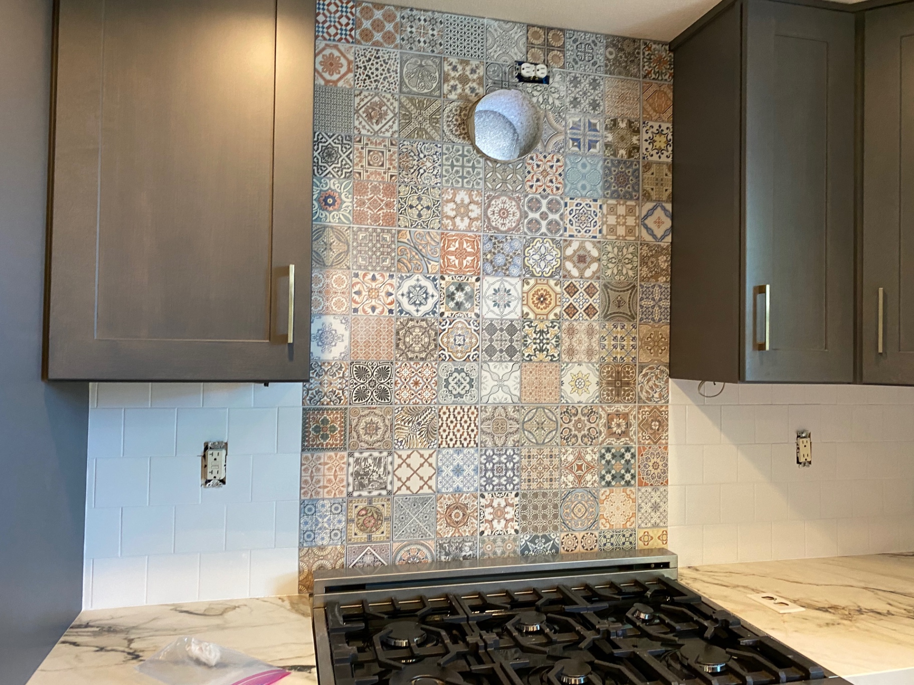 Kitchen range backsplash featuring colorful patchwork patterned tile floor-to-ceiling