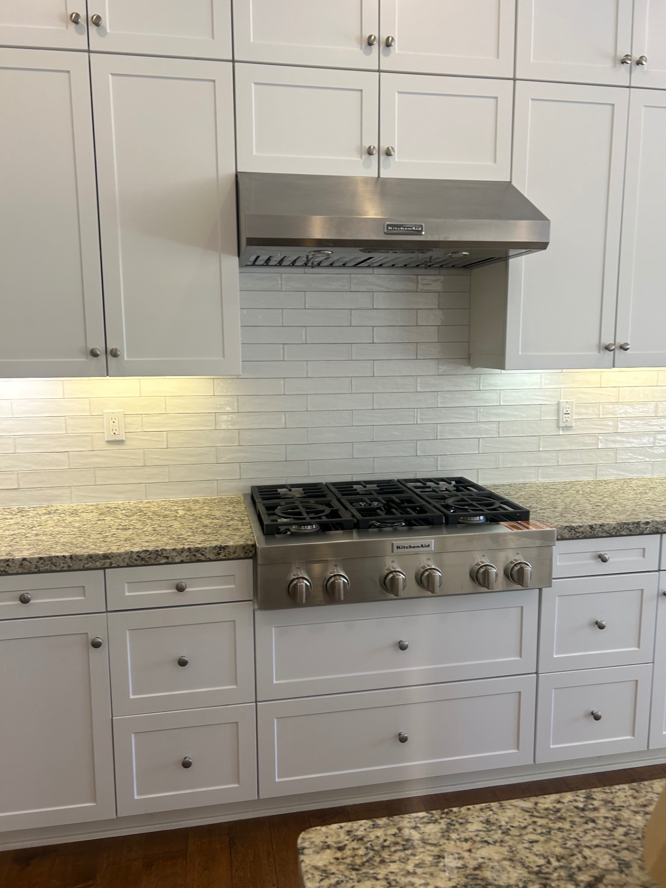 Detail of white handmade subway tile backsplash behind KitchenAid stainless hood