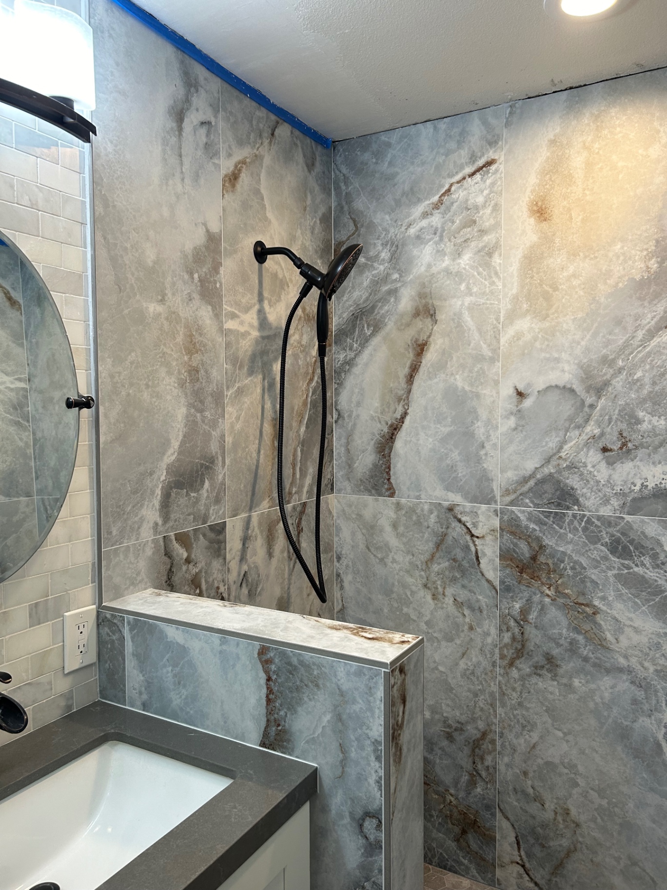 Onyx-look porcelain shower wall detail next to vanity with subway tile