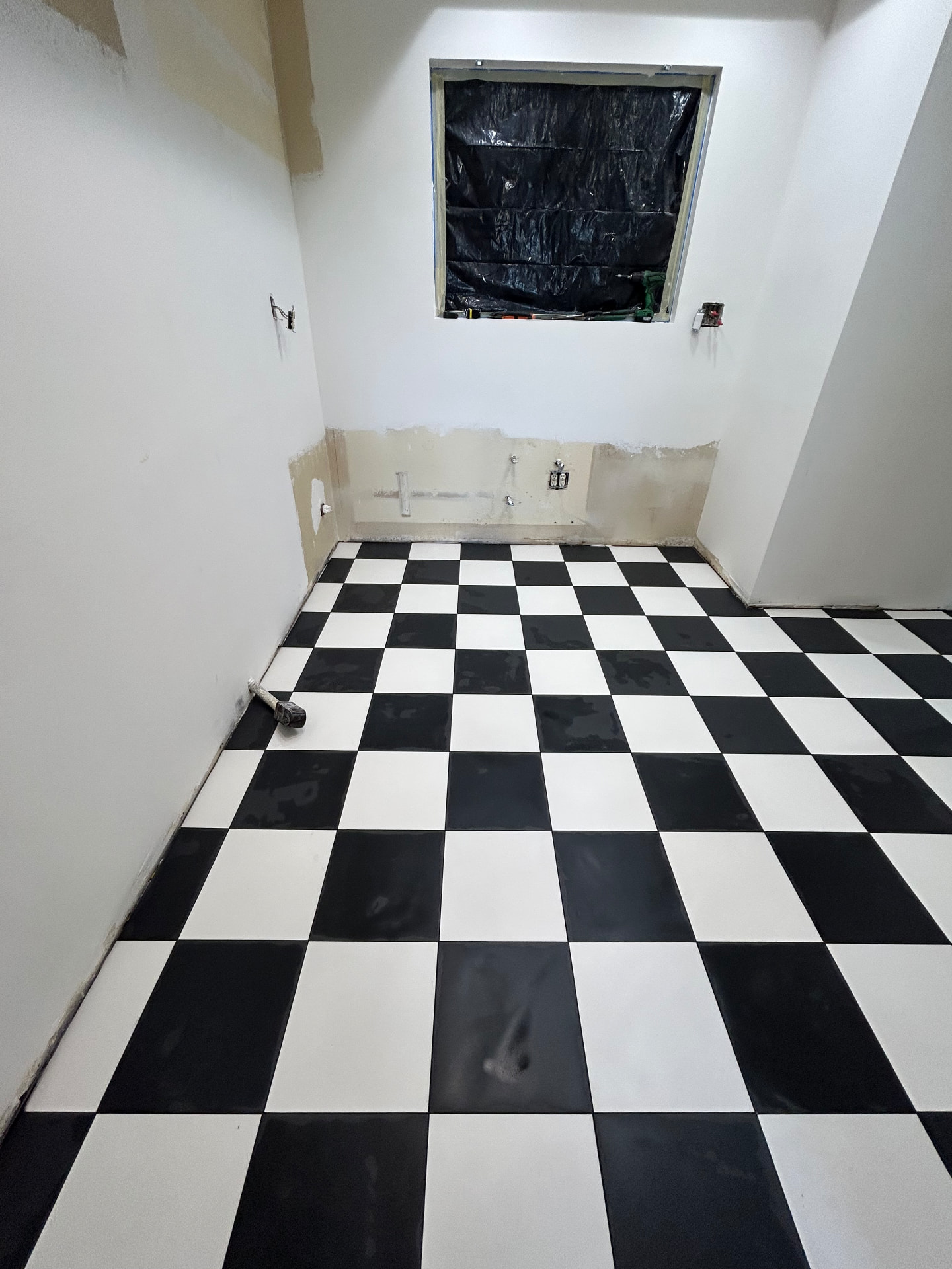 Black and white checkerboard tile floor in laundry room installation