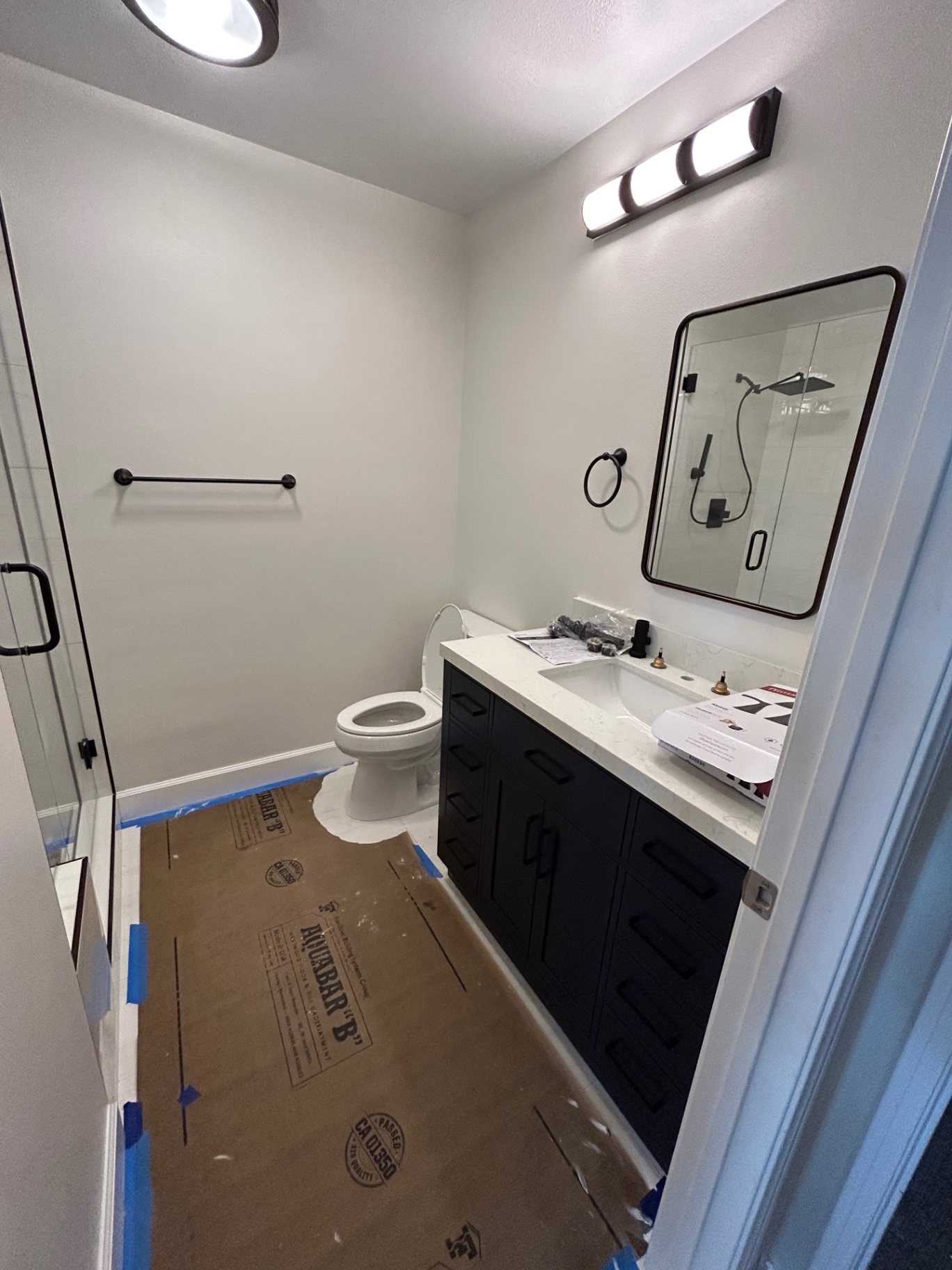 Bathroom with navy shaker vanity, quartz counter and frameless glass shower