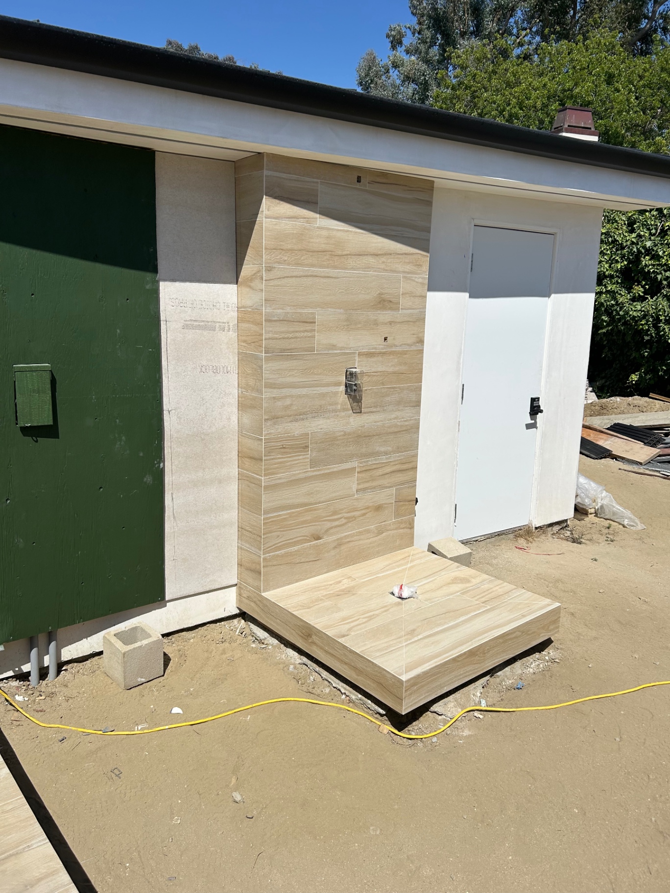Outdoor shower wall and base tiled in wood-look porcelain
