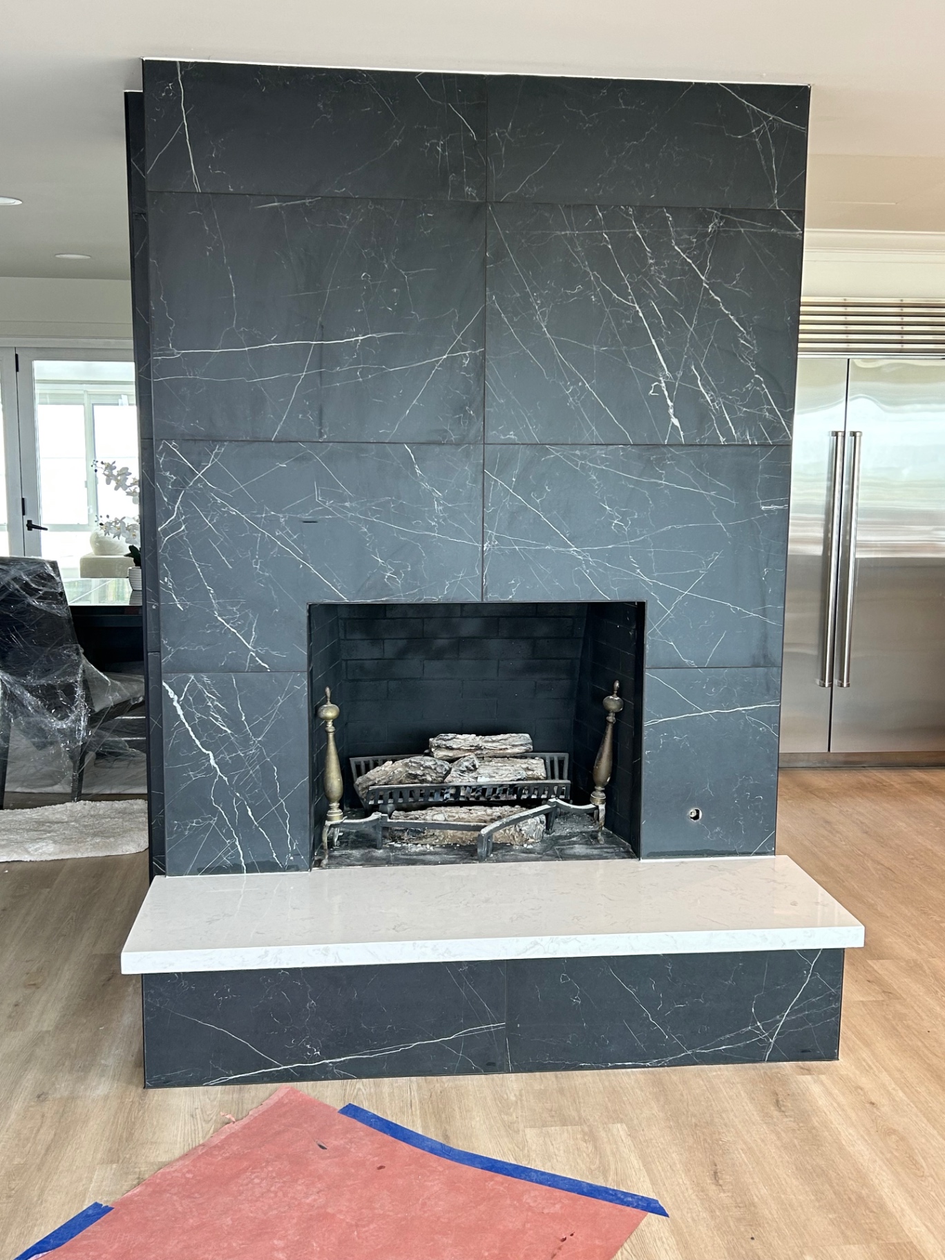 Front view of black marble-look porcelain fireplace with white quartz bench