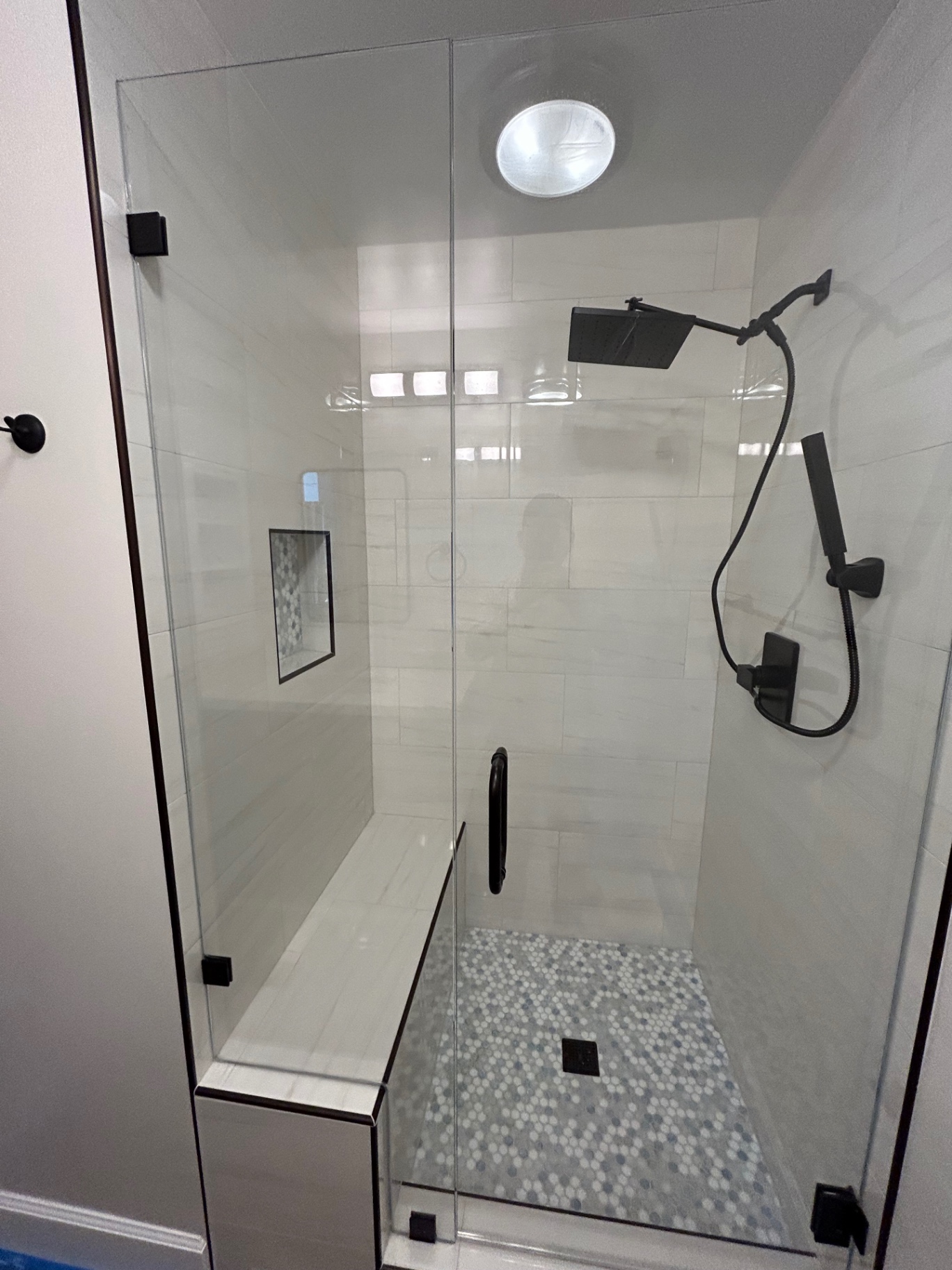 White marble-look shower with bench, niche, blue hex floor and glass enclosure