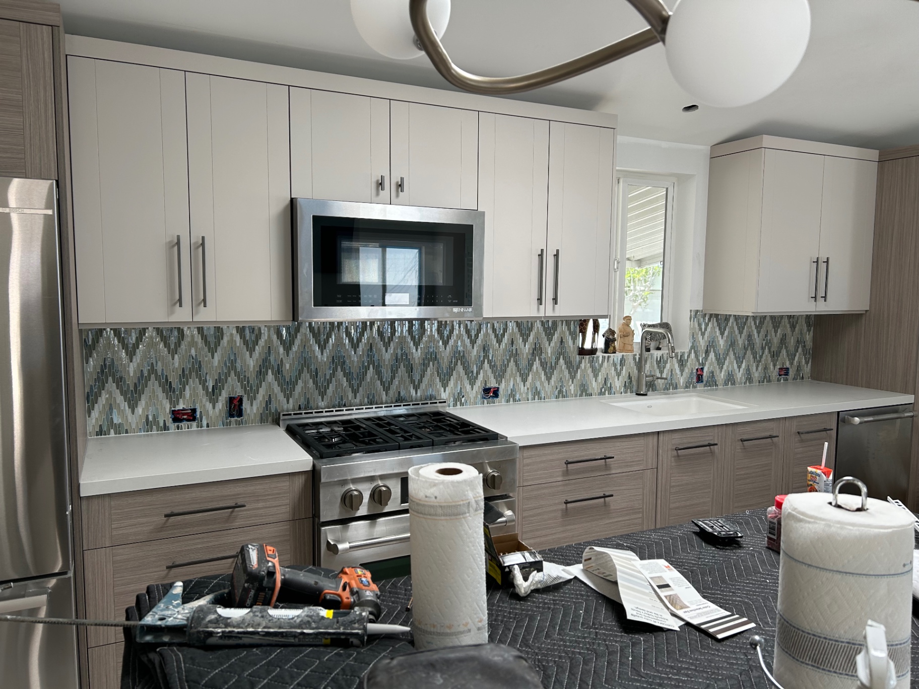 Modern kitchen with multicolor chevron glass mosaic backsplash and two-tone cabinets