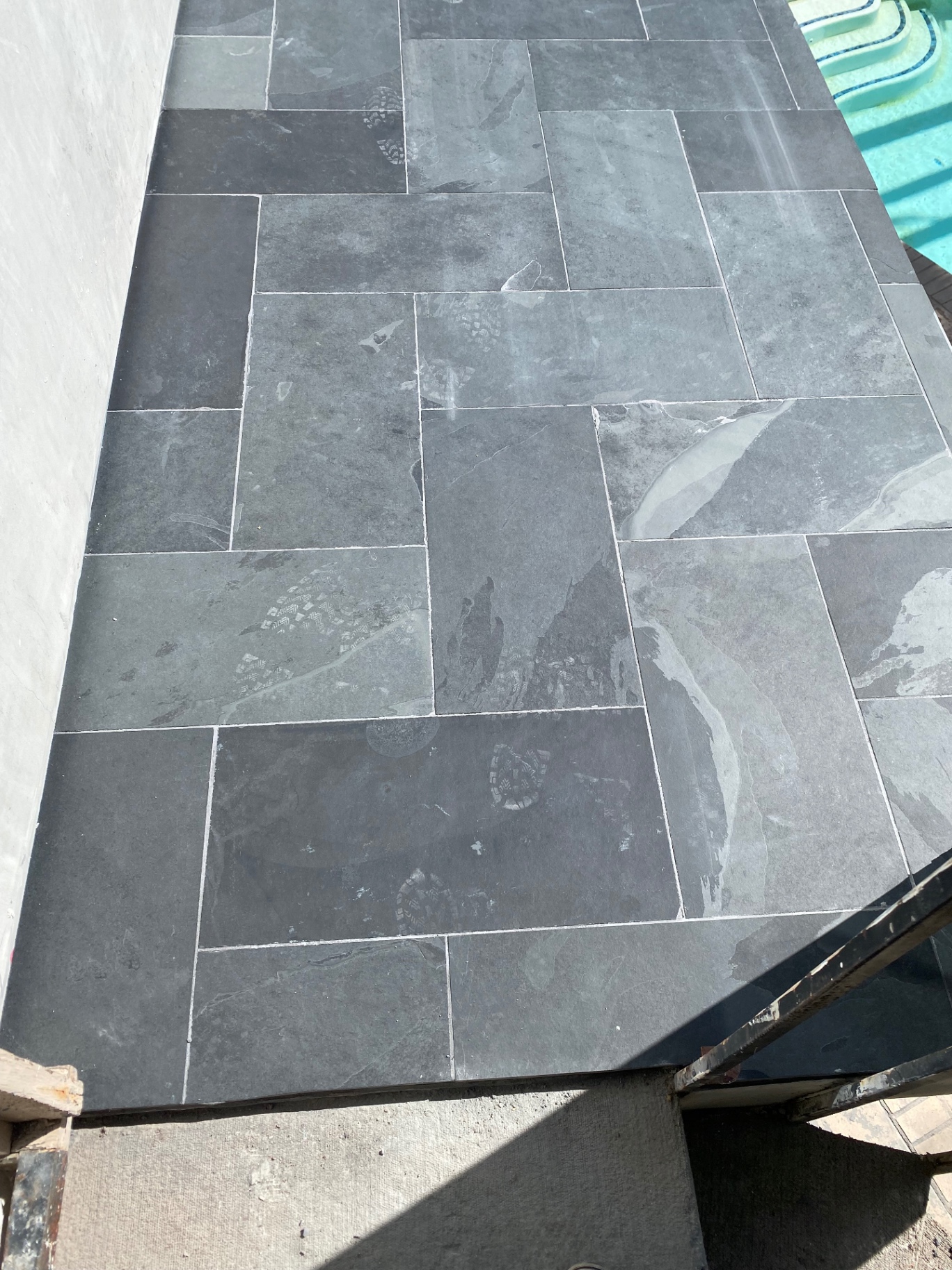 Close-up of black slate pool deck tile in herringbone layout