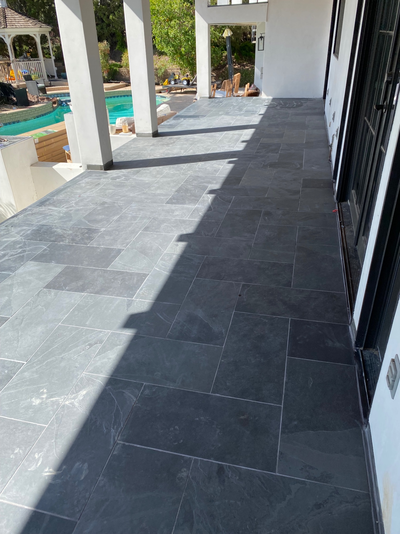Black slate tile patio overlooking pool and gazebo