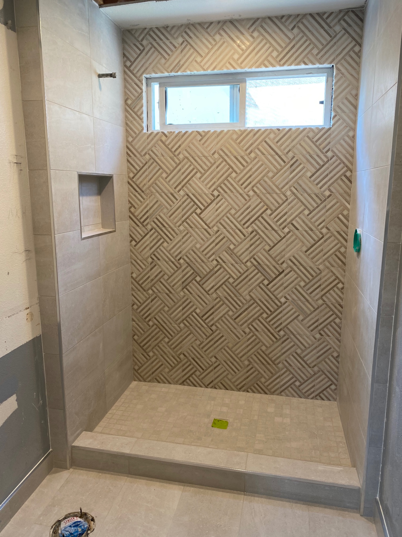 Walk-in shower with wood-look basketweave mosaic feature wall and large-format gray tile