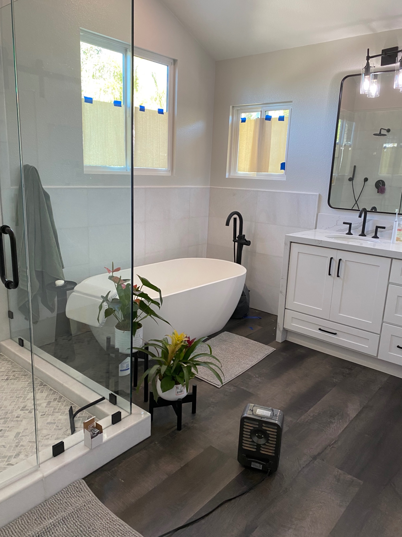 Modern bathroom remodel with freestanding tub, white vanity and dark floor tile