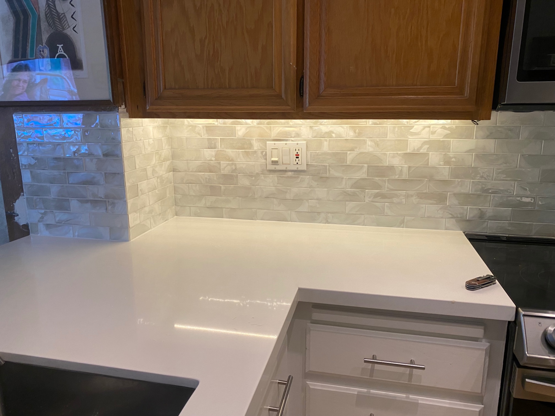 Pearlescent subway tile backsplash wrapping kitchen corner with quartz counters