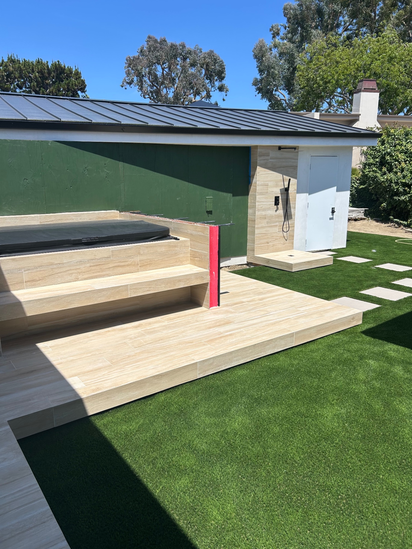 Finished backyard with tiled deck, hot tub and outdoor shower