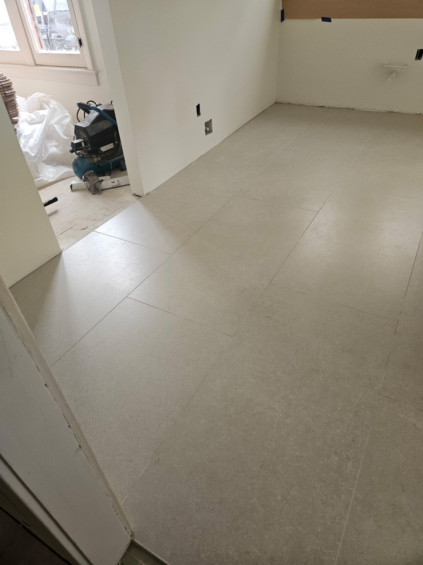 Wide view of large format limestone-look floor tile installation