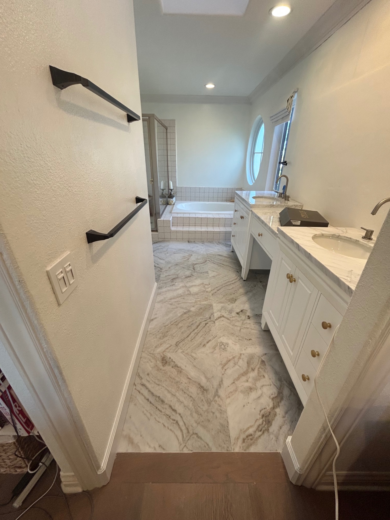 Master bathroom remodel with marble-look porcelain floor, soaking tub and dual marble vanities
