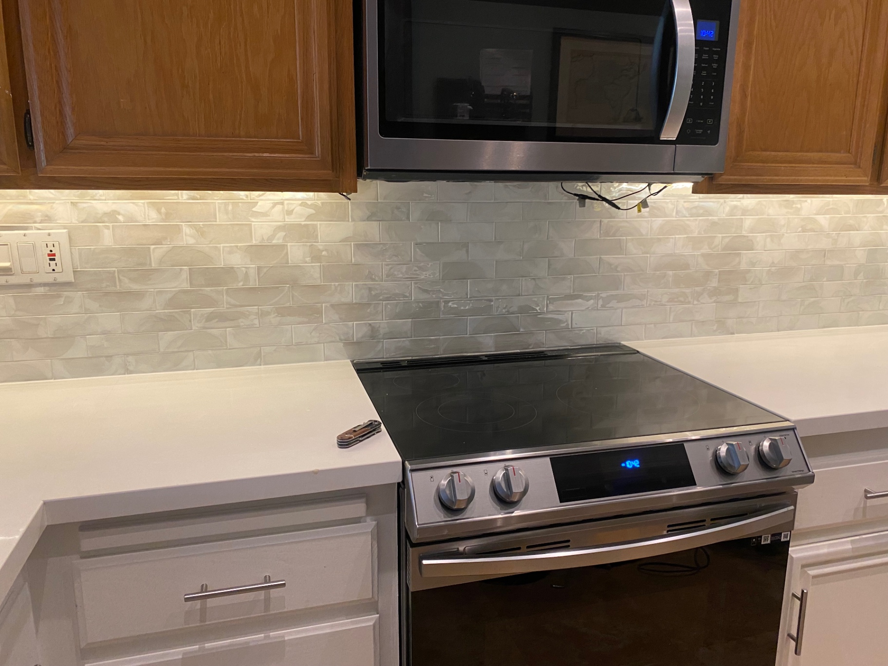 Pearlescent handmade subway tile backsplash behind stainless range and microwave