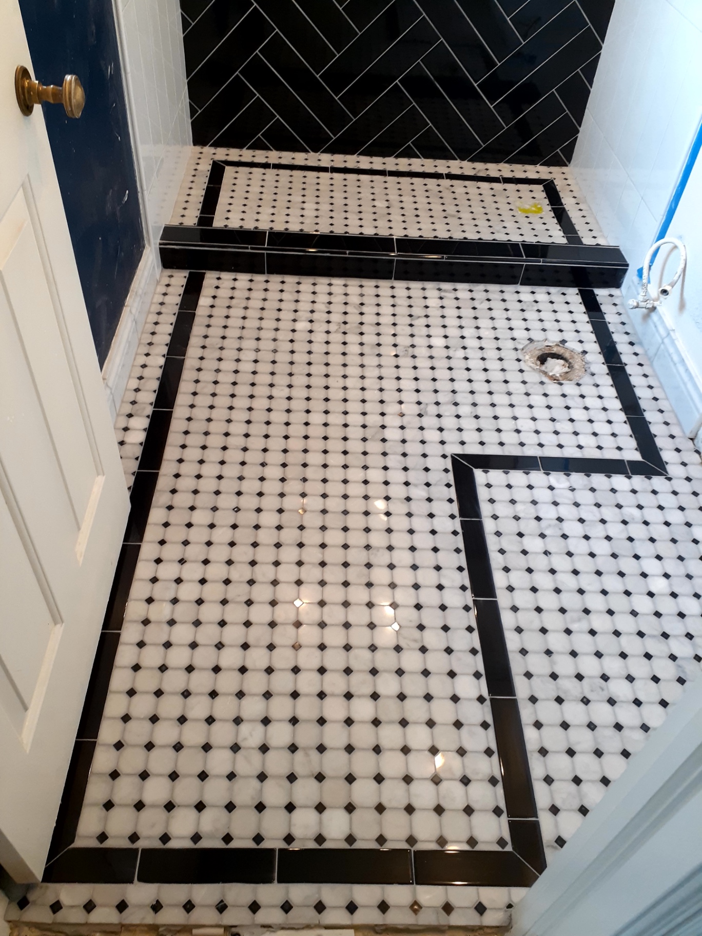 Black and white shower pan with octagon mosaic floor and black border detail