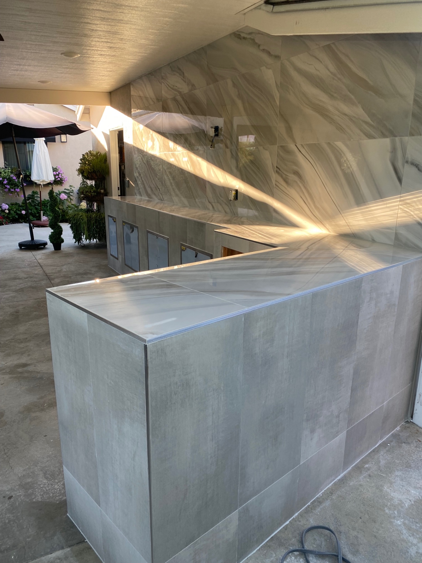 L-shaped outdoor bar clad in marble-look porcelain tile
