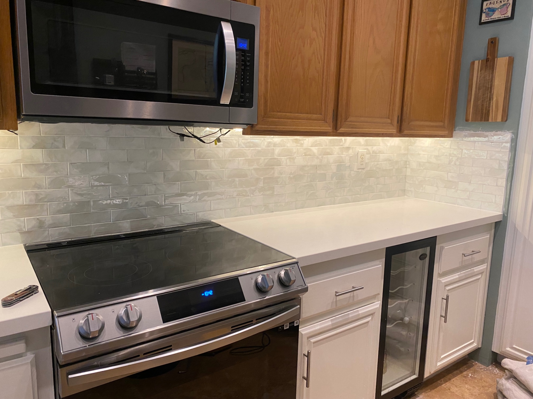 Pearl glass tile backsplash behind range with stainless appliances