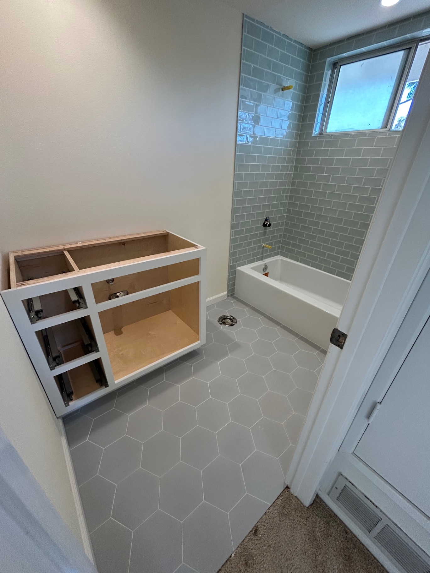 Bathroom with seafoam subway shower surround and gray hexagon floor