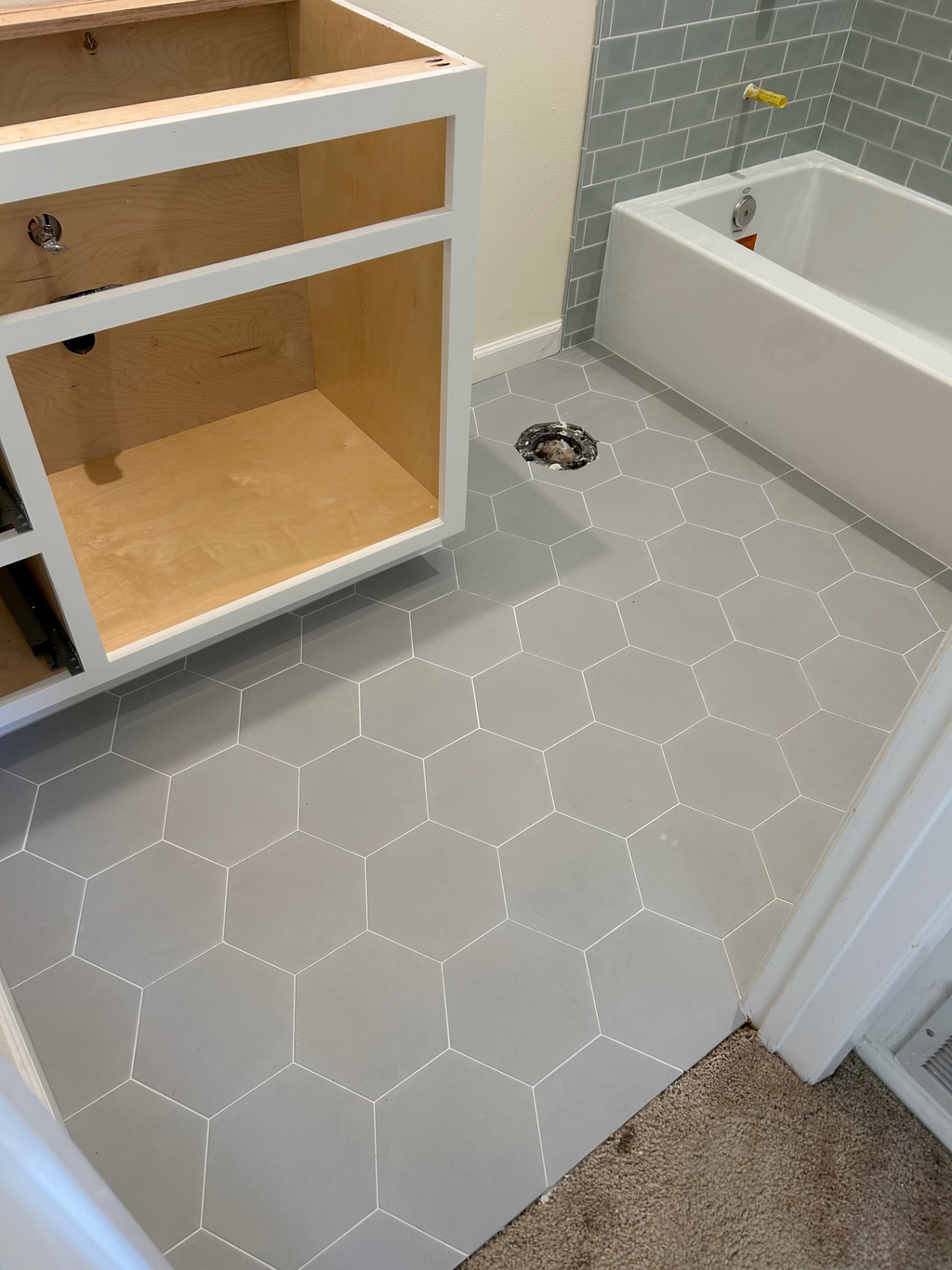 Gray hexagon tile bathroom floor with soft blue subway tub surround