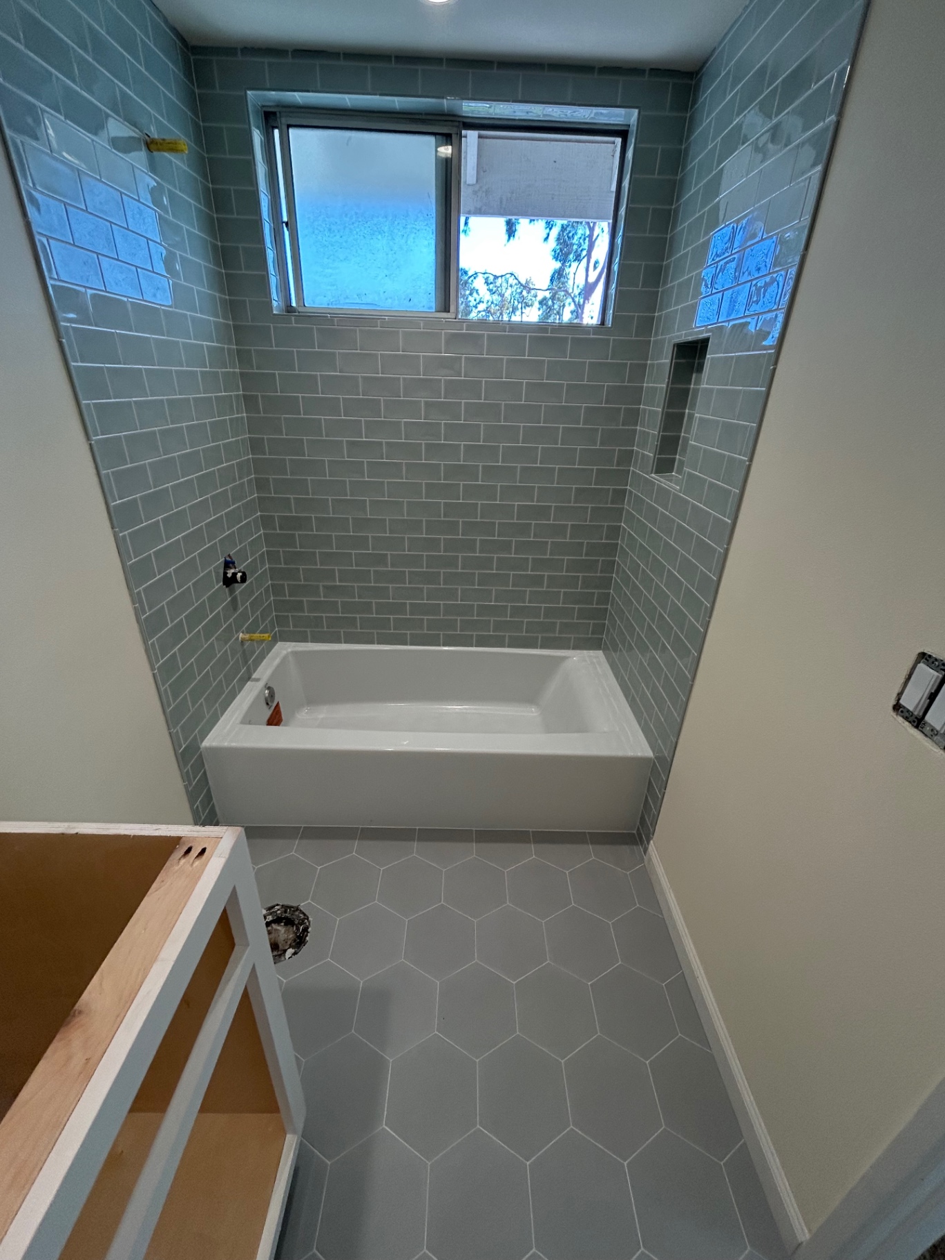 Soft blue subway tile tub surround with hexagon floor
