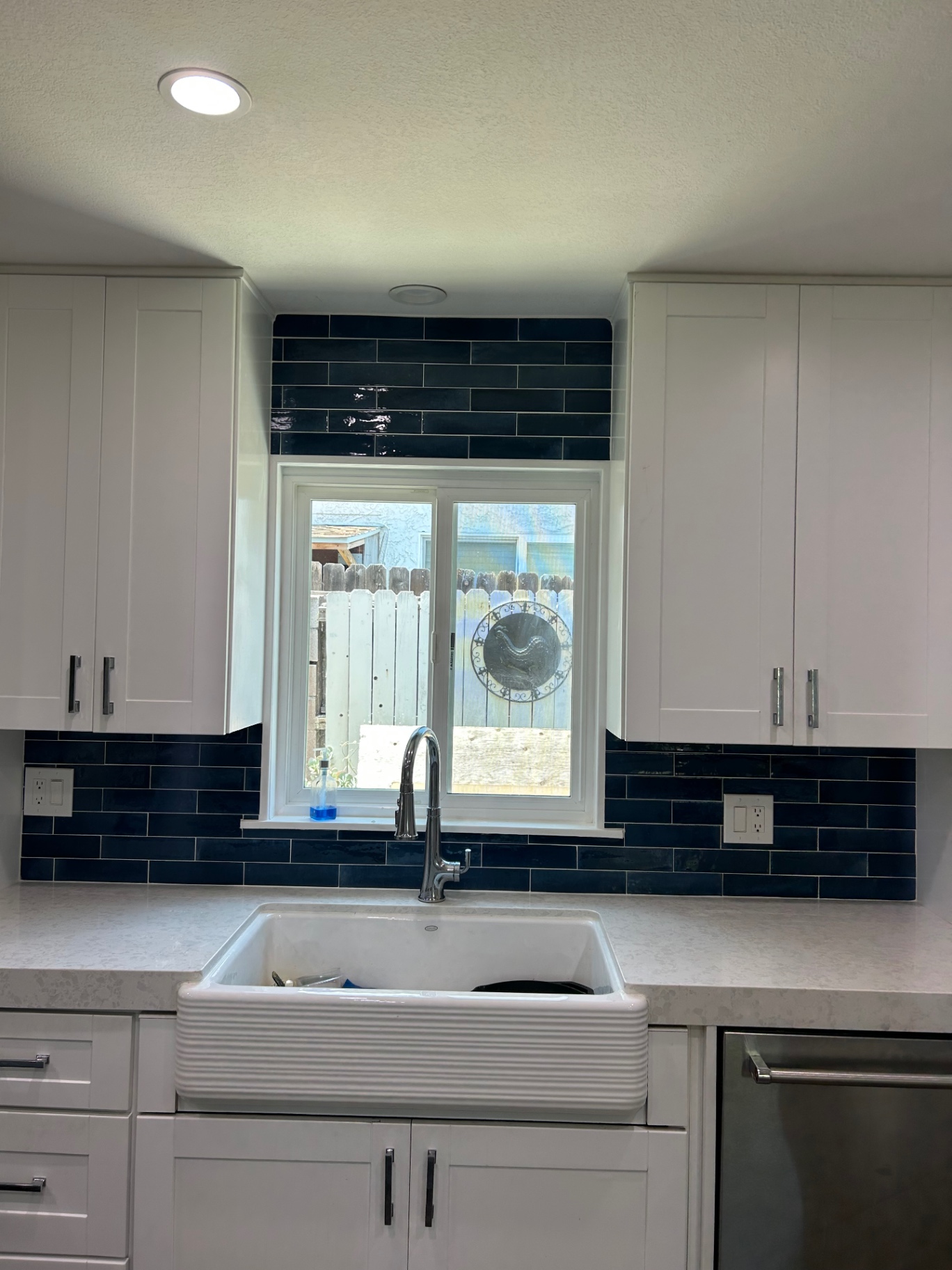 Navy blue glazed tile backsplash with farmhouse sink
