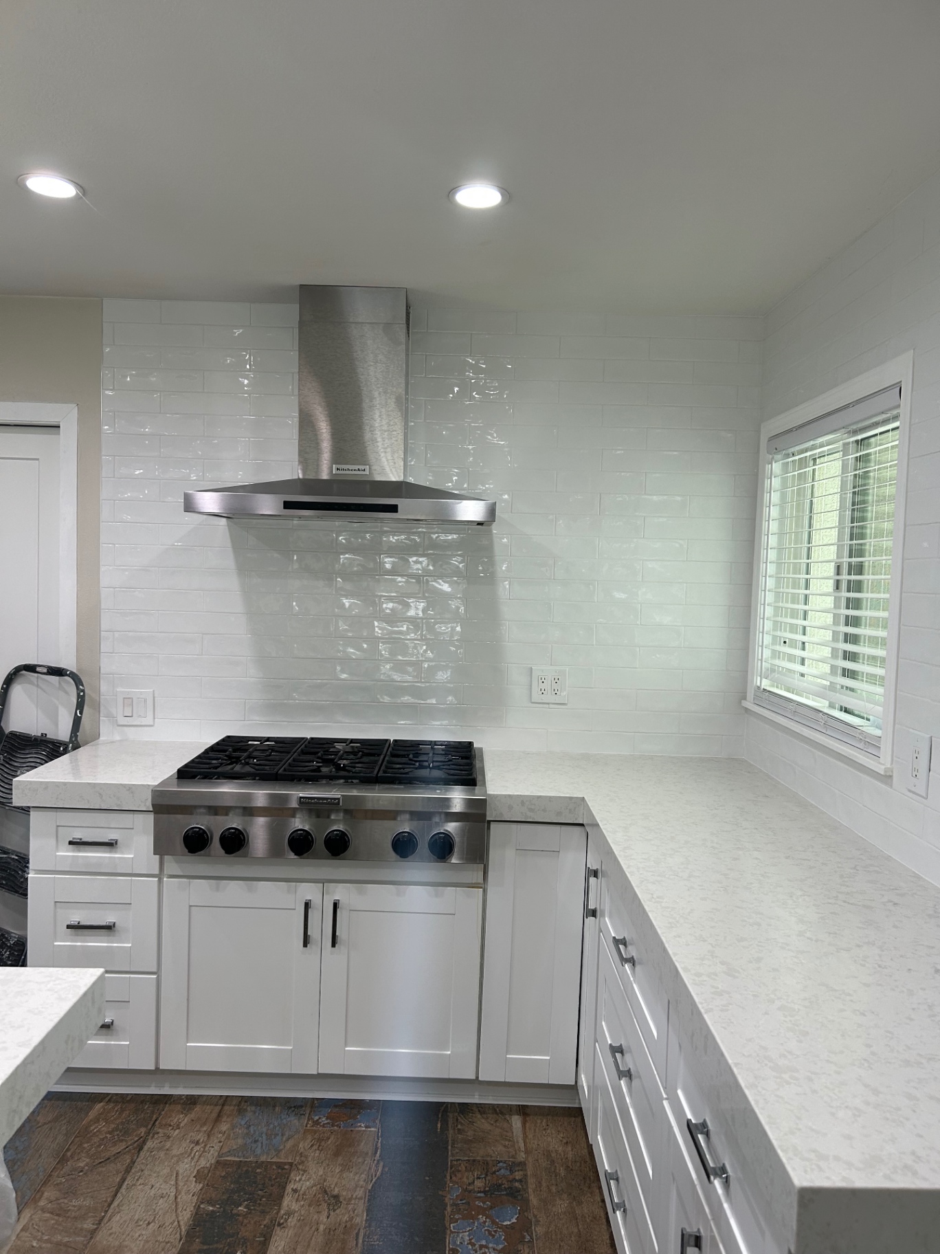 White handmade subway tile kitchen backsplash with stainless hood