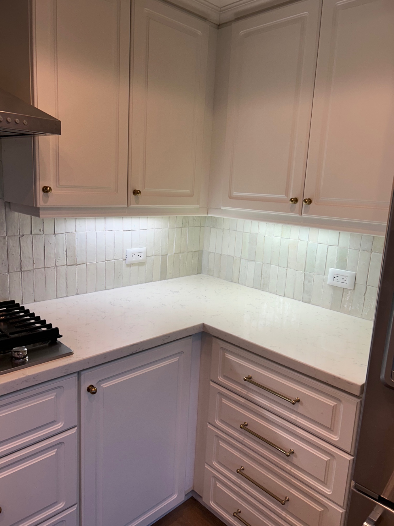 Corner detail of white zellige backsplash with quartz counters