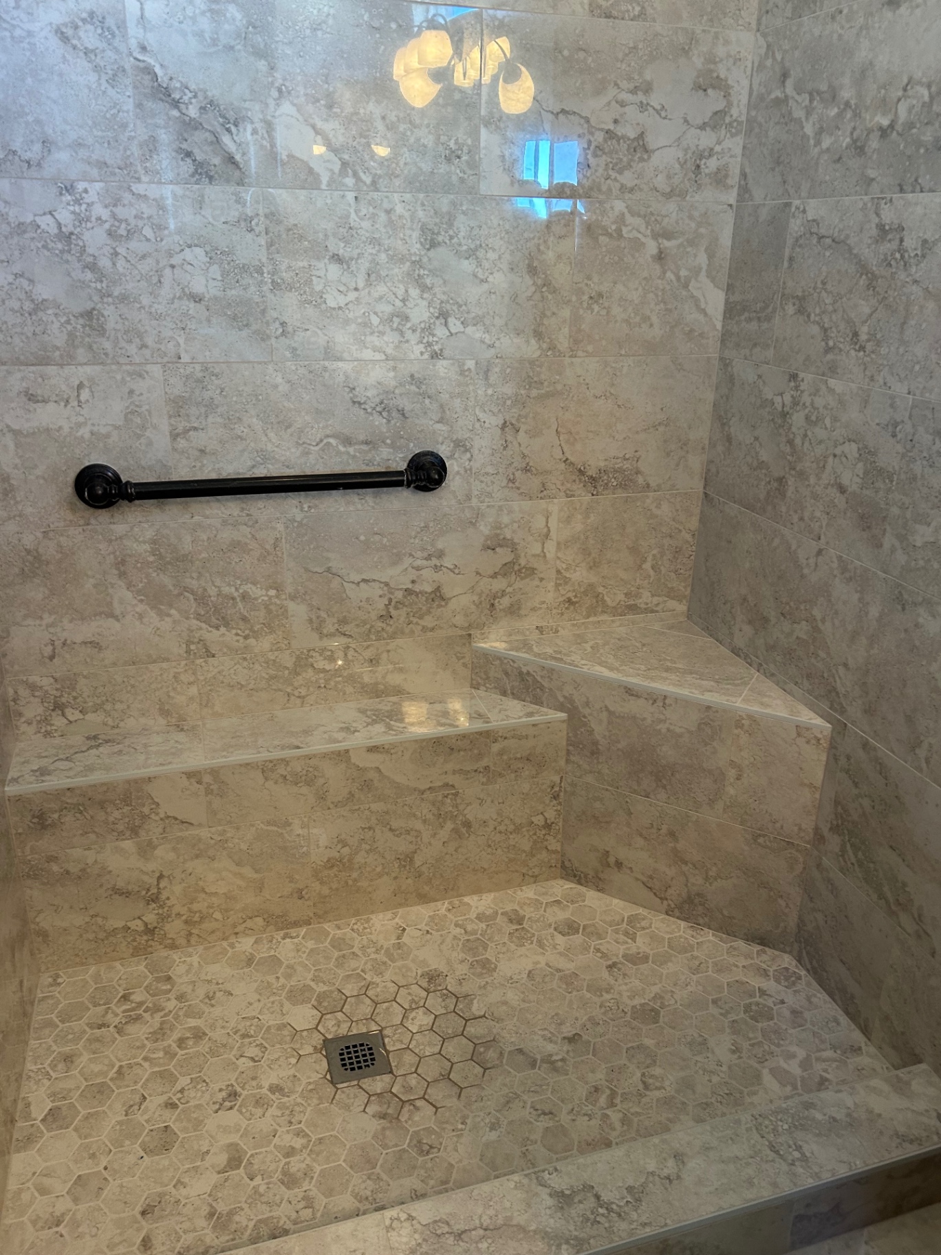 Marble shower bench with hexagon mosaic floor and grab bar