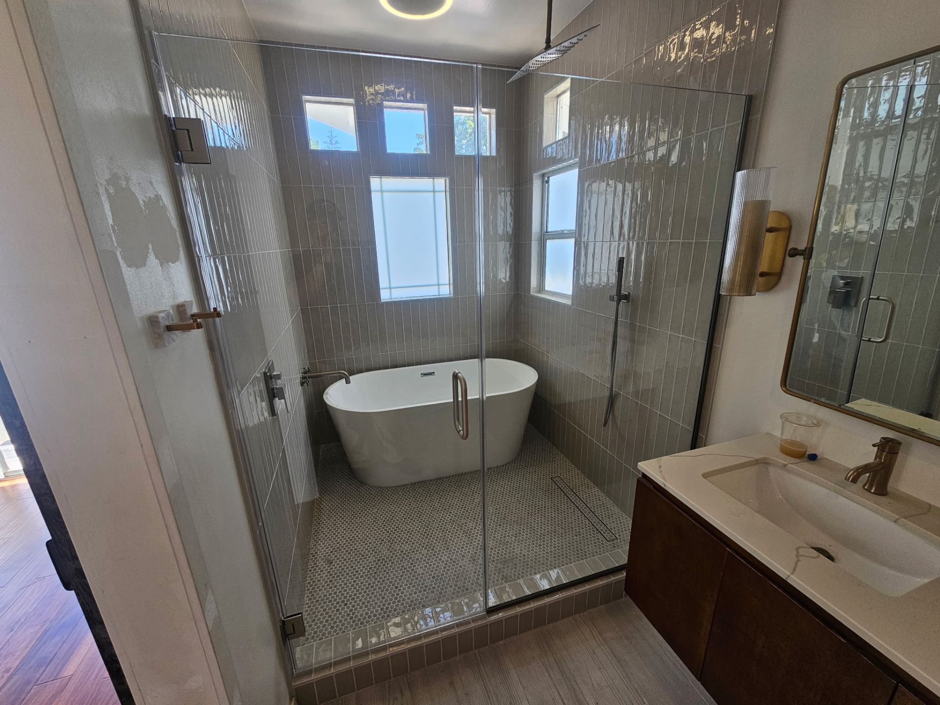 Luxury wet room with freestanding tub, glass enclosure and vertical stacked tile