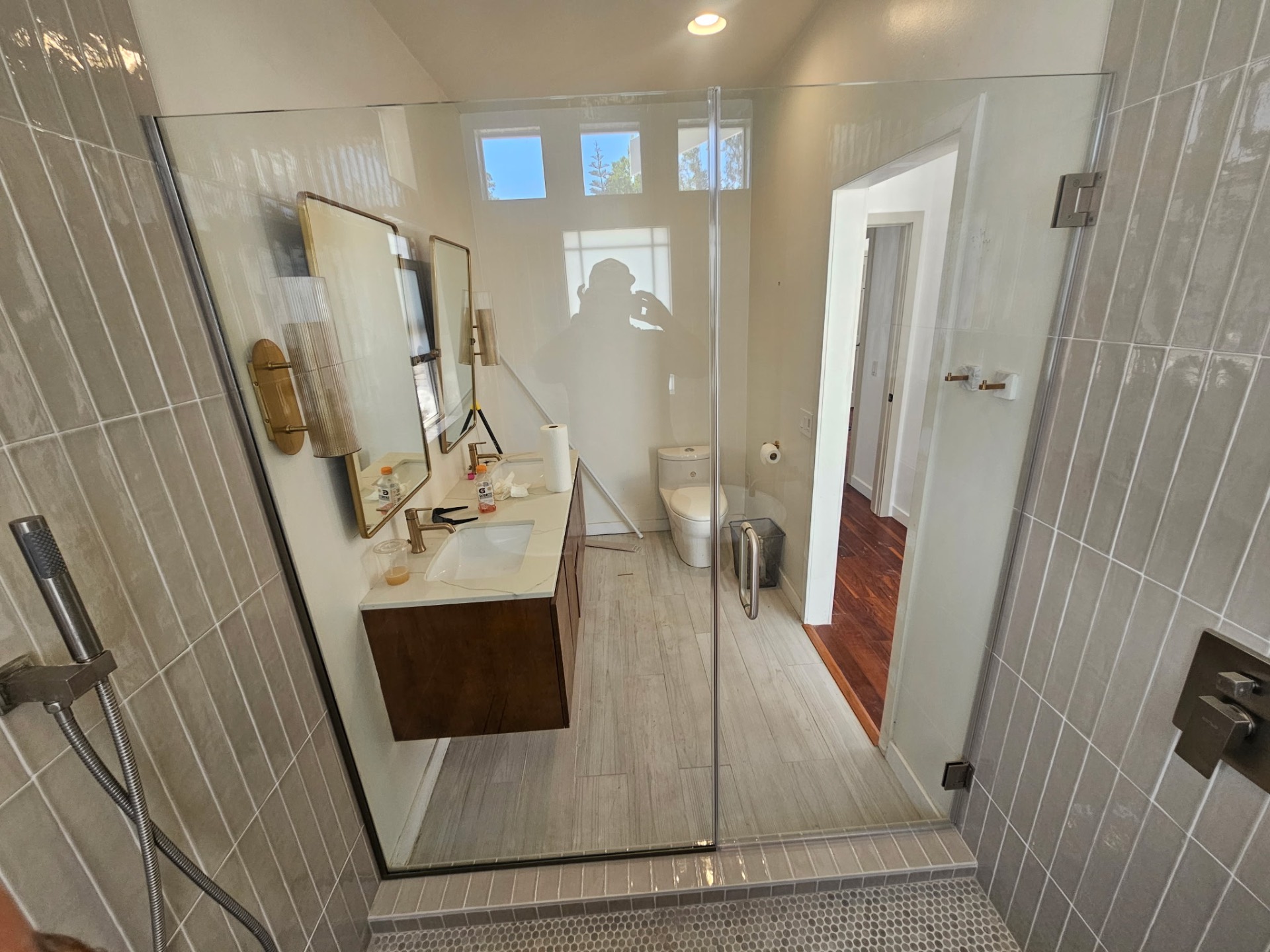 Walk-in wet room shower with floating walnut vanity and brass fixtures